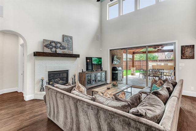 living room with a high ceiling, dark wood-type flooring, and a healthy amount of sunlight