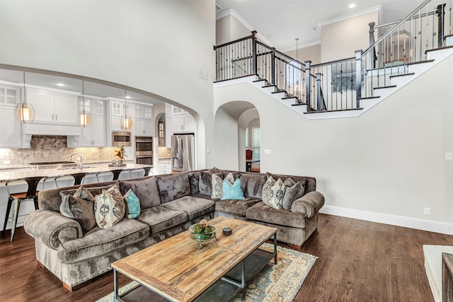 living room featuring crown molding, dark hardwood / wood-style floors, and a towering ceiling