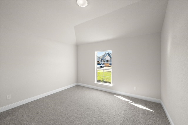 spare room featuring carpet floors and vaulted ceiling