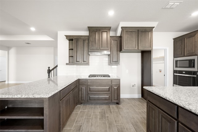 kitchen with light stone counters, decorative backsplash, dark brown cabinets, and appliances with stainless steel finishes