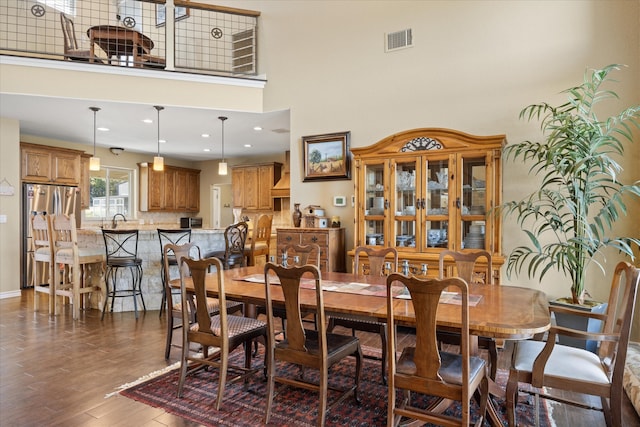 dining space with sink, dark wood-type flooring, and a high ceiling