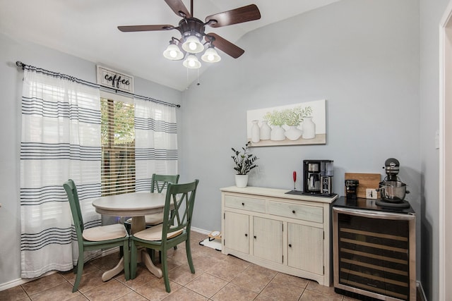 dining room with ceiling fan, beverage cooler, light tile patterned floors, and vaulted ceiling