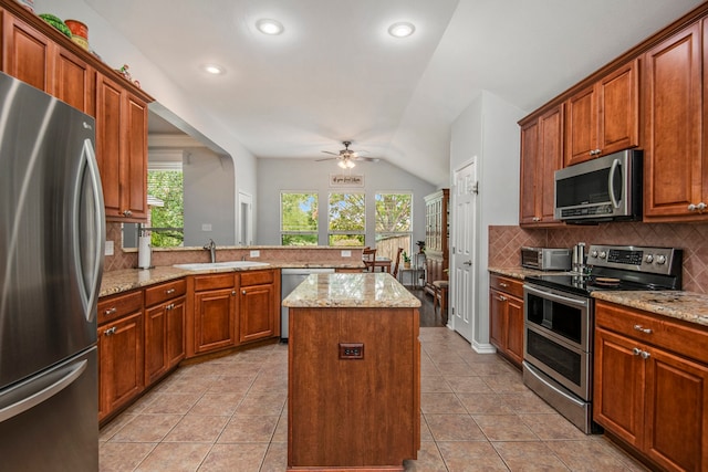 kitchen with appliances with stainless steel finishes, vaulted ceiling, a healthy amount of sunlight, and a center island