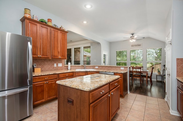 kitchen featuring light hardwood / wood-style floors, lofted ceiling, a center island, ceiling fan, and stainless steel fridge