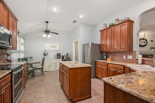 kitchen with stainless steel appliances, a kitchen island, decorative backsplash, sink, and vaulted ceiling