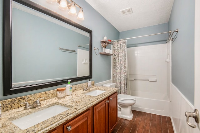 full bathroom with hardwood / wood-style flooring, a textured ceiling, vanity, shower / bath combo, and toilet