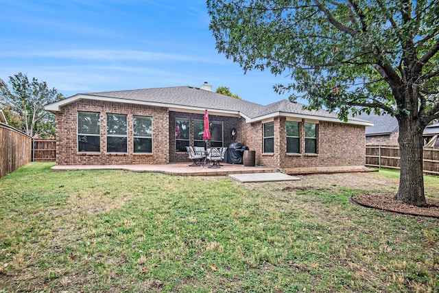 rear view of house featuring a lawn and a patio