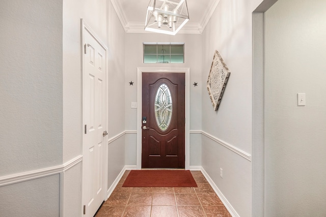 entrance foyer featuring dark tile patterned floors, an inviting chandelier, and crown molding