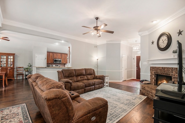 living room featuring ornamental molding, ceiling fan, dark hardwood / wood-style floors, and a brick fireplace