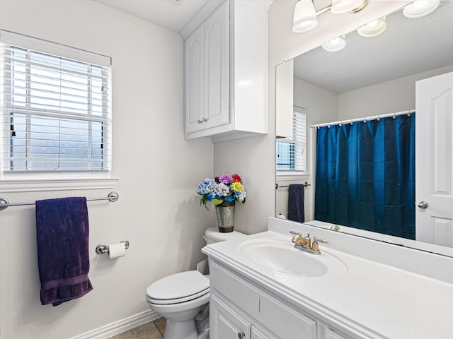 bathroom with vanity, toilet, a healthy amount of sunlight, and tile patterned flooring