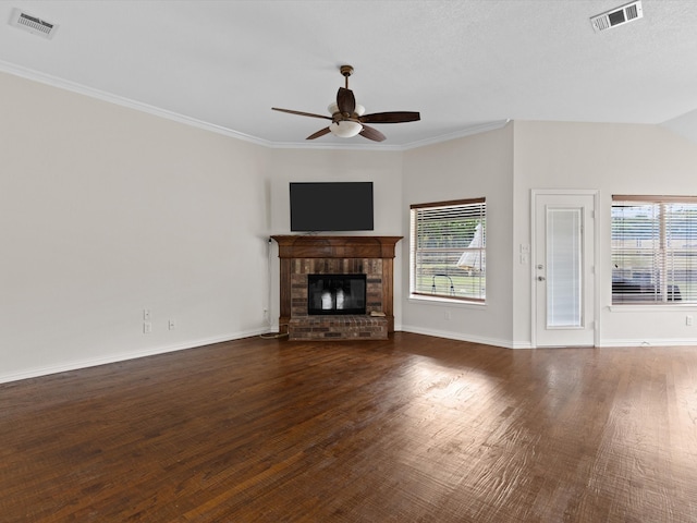 unfurnished living room with ornamental molding, vaulted ceiling, dark hardwood / wood-style flooring, a fireplace, and ceiling fan