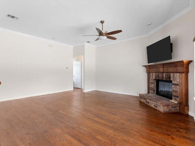 unfurnished living room with crown molding, a brick fireplace, dark hardwood / wood-style floors, and ceiling fan