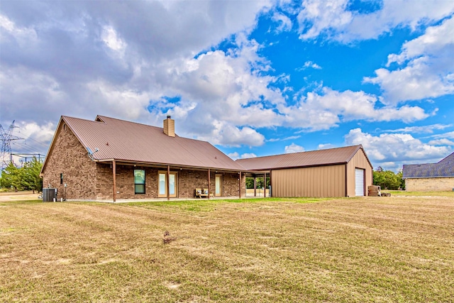 rear view of property featuring a garage, an outdoor structure, cooling unit, and a lawn