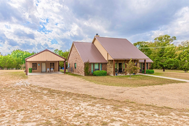 view of front of property with driveway, a front lawn, an outdoor structure, metal roof, and a chimney