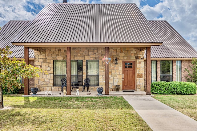 view of front of home with stone siding, metal roof, and a front lawn