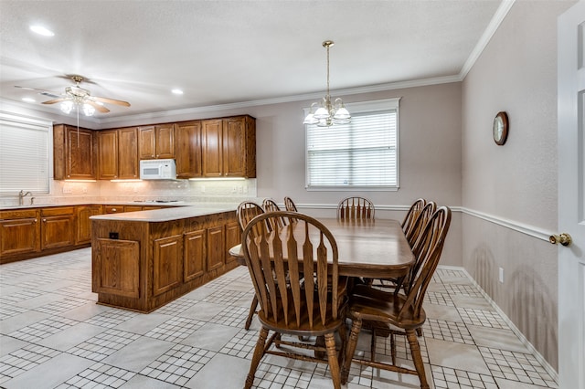 dining room with ornamental molding, sink, and ceiling fan with notable chandelier