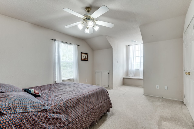 bedroom featuring ceiling fan, a textured ceiling, vaulted ceiling, and light colored carpet