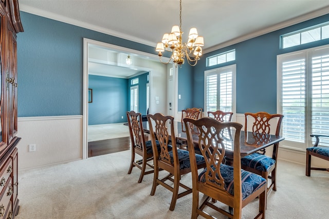 carpeted dining space with crown molding, a healthy amount of sunlight, and a chandelier