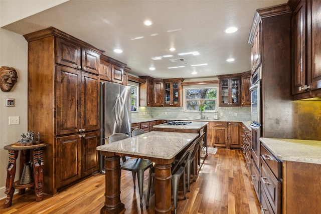 kitchen featuring light stone countertops, a kitchen island, a breakfast bar area, and stainless steel refrigerator