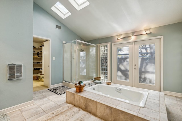 bathroom with independent shower and bath, tile patterned flooring, vaulted ceiling with skylight, and french doors