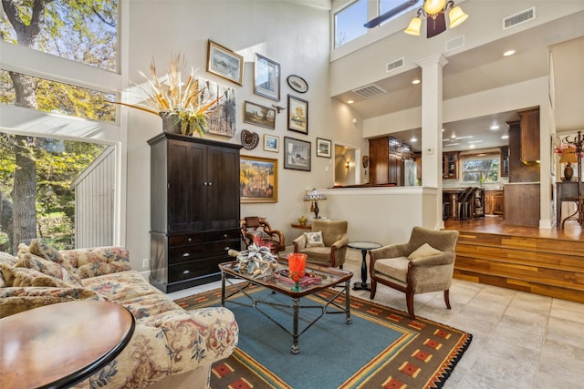 living room with light tile patterned floors, a high ceiling, ceiling fan, and ornate columns