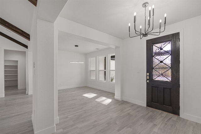 entryway with a notable chandelier, lofted ceiling with beams, light wood-type flooring, and a wealth of natural light