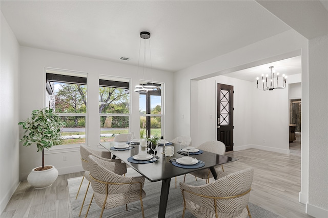 dining space with a notable chandelier and light hardwood / wood-style flooring