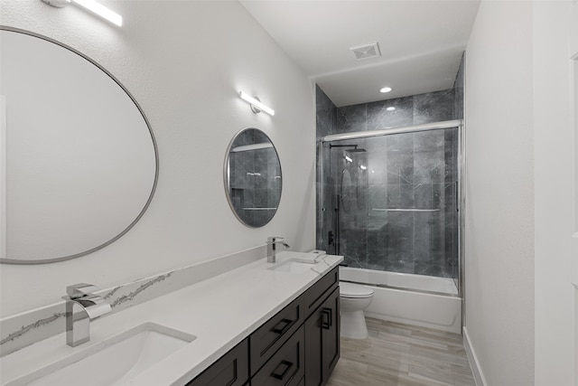 full bathroom with hardwood / wood-style floors, vanity, enclosed tub / shower combo, and toilet