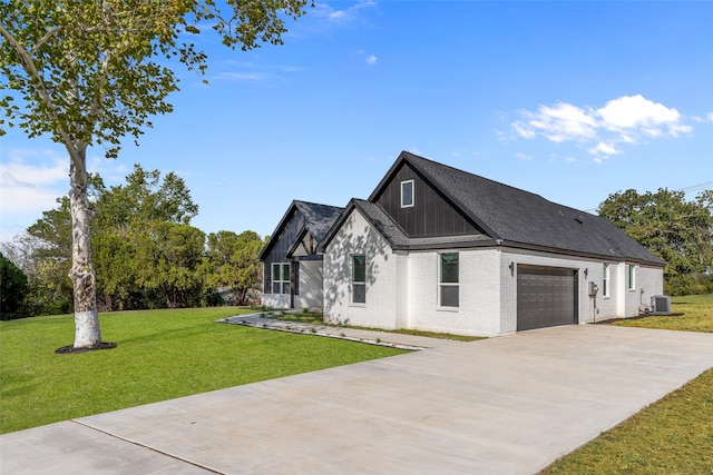 view of front of property with cooling unit, a garage, and a front lawn