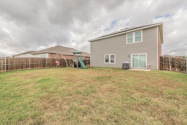 rear view of house featuring a yard and a playground