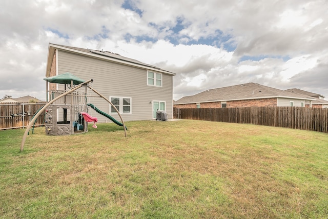 back of house featuring a lawn, cooling unit, and a playground