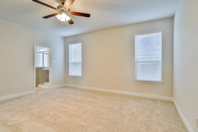 empty room featuring ceiling fan, plenty of natural light, and light colored carpet