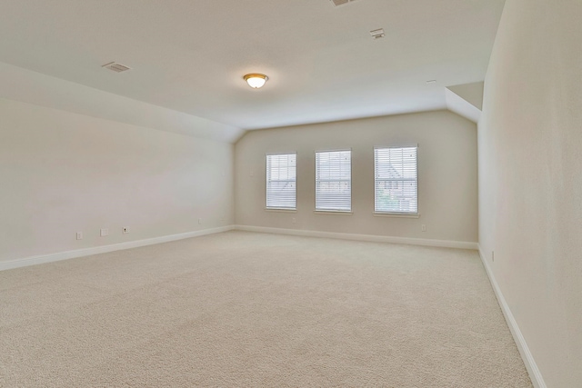 unfurnished room with vaulted ceiling and light carpet