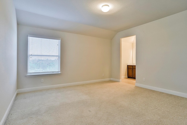 unfurnished room featuring light carpet, lofted ceiling, and a textured ceiling