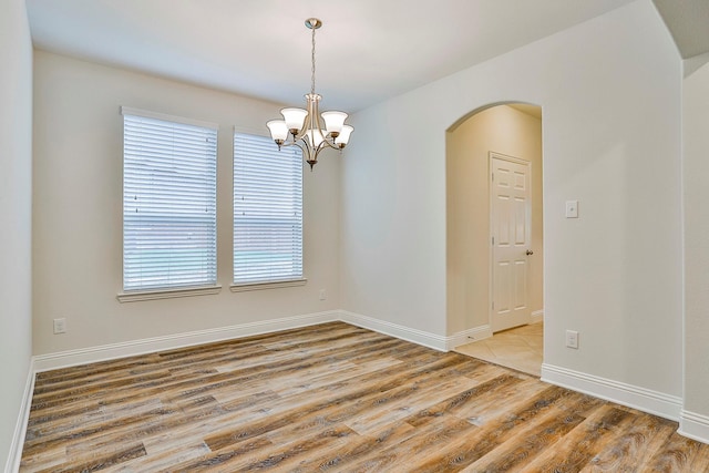 empty room featuring hardwood / wood-style floors and a notable chandelier