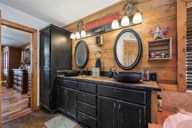 bathroom featuring double vanity, wooden walls, and a sink