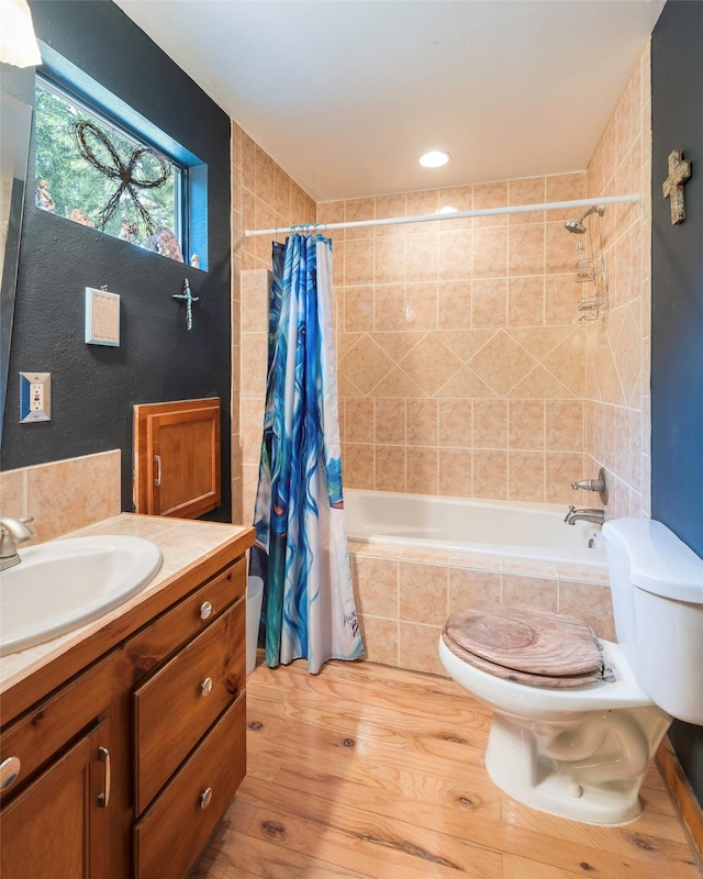 full bathroom featuring hardwood / wood-style flooring, vanity, shower / bath combination with curtain, and toilet