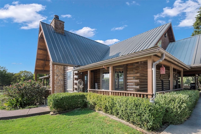 view of home's exterior featuring a standing seam roof, log siding, a chimney, and metal roof