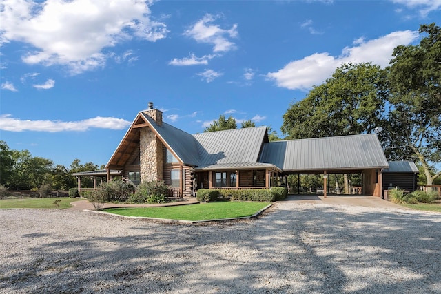 view of front of property with a front lawn, driveway, metal roof, a carport, and a chimney