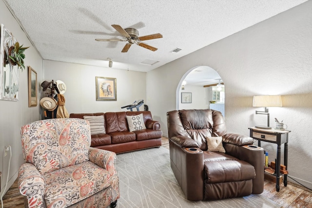 living room with light hardwood / wood-style flooring, a textured ceiling, and ceiling fan