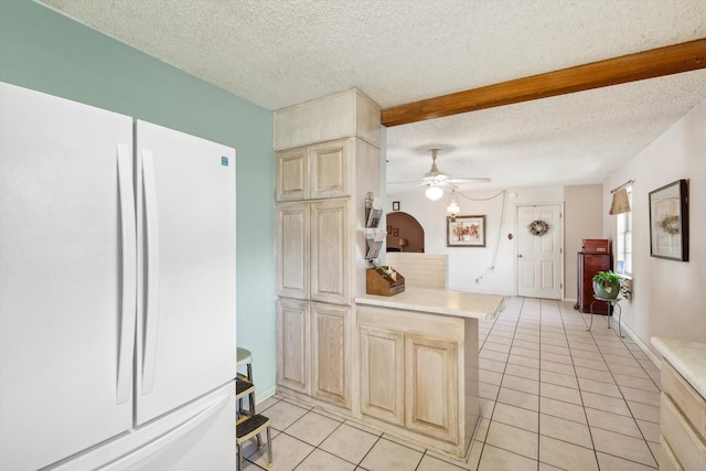 kitchen with a textured ceiling, white fridge, and light tile patterned flooring