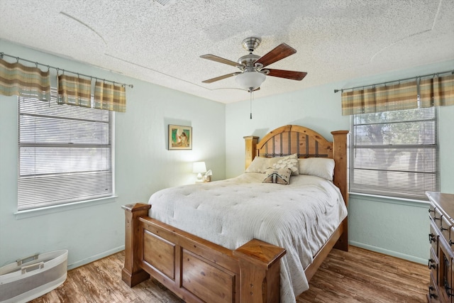 bedroom with ceiling fan, wood-type flooring, and a textured ceiling