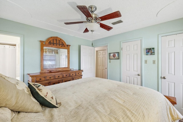 bedroom with ceiling fan, multiple closets, and a textured ceiling