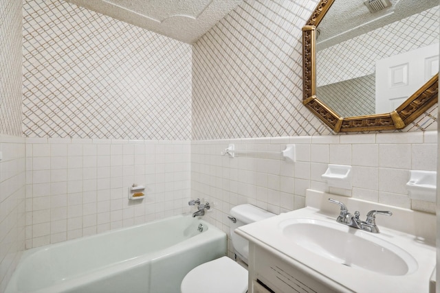 full bathroom featuring toilet, bathing tub / shower combination, tile walls, vanity, and a textured ceiling