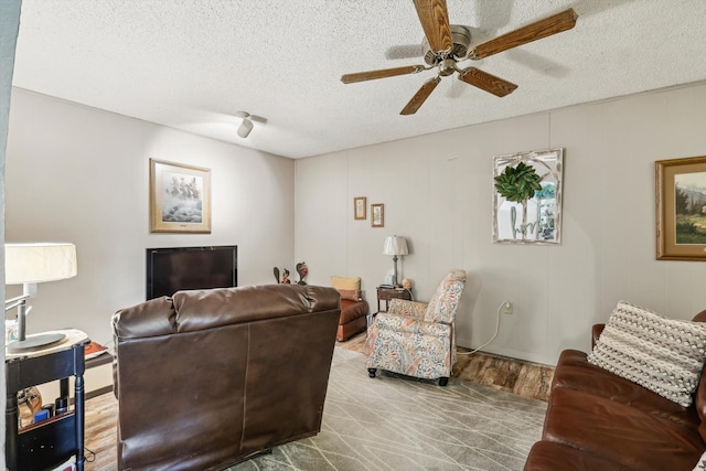 living room featuring a textured ceiling, light wood-type flooring, and ceiling fan