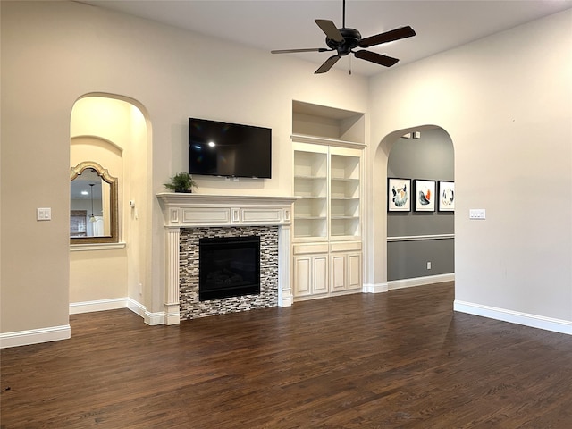 unfurnished living room featuring ceiling fan, a fireplace, built in features, and dark hardwood / wood-style flooring