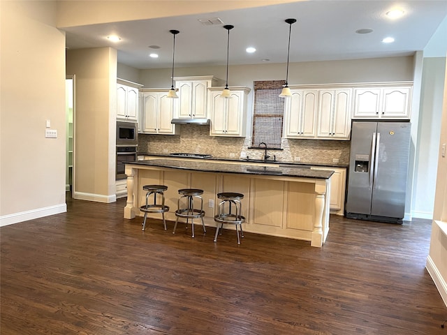 kitchen featuring a kitchen island, dark wood-type flooring, backsplash, pendant lighting, and appliances with stainless steel finishes