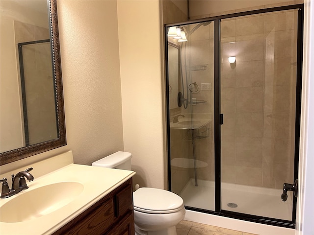 bathroom with toilet, vanity, and a shower with door