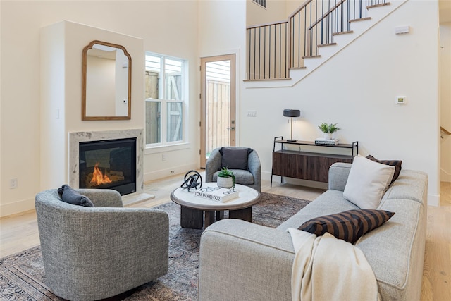 living room featuring a wealth of natural light, a fireplace, a towering ceiling, and hardwood / wood-style floors