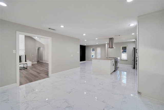 kitchen with wall chimney range hood, stainless steel electric stove, white cabinets, light hardwood / wood-style flooring, and a center island